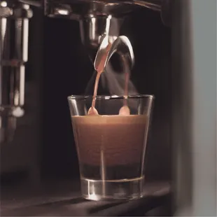 a coffee being poured into a glass