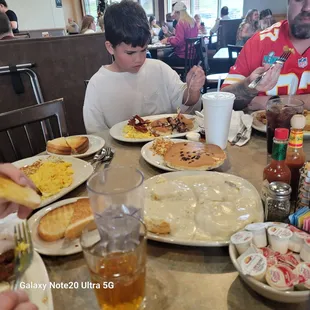 Grandboy eating chocolate chip pancakes, scrambled eggs , bacon