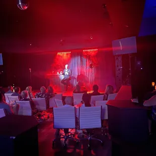 a group of people sitting in a room with red lighting