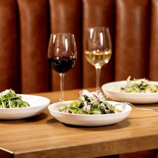 two plates of salad and two glasses of wine