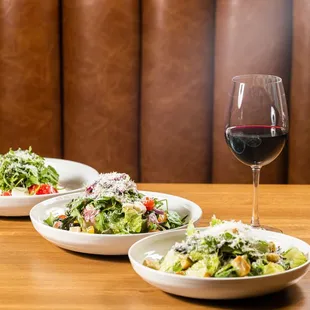 three bowls of salad and a glass of wine