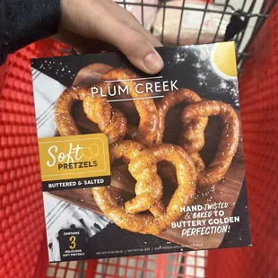 a hand holding a box of soft pretzels