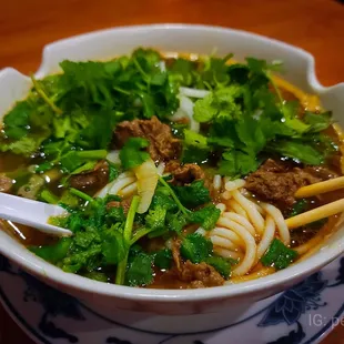 a bowl of noodle soup with chopsticks