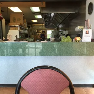 a view of a restaurant counter with a pink chair in front of it