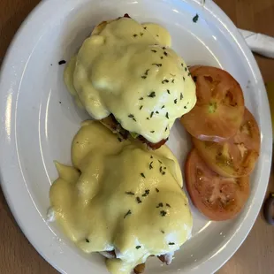 Bacon and avocado eggs Benedict with a side of roasted tomatoes