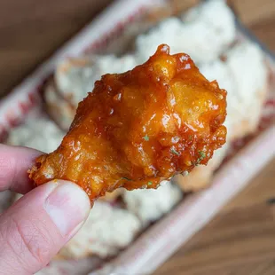 a hand holding a piece of fried chicken