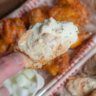 a hand holding a piece of fried chicken