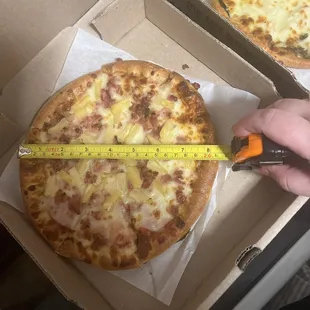 a person measuring the size of a pizza