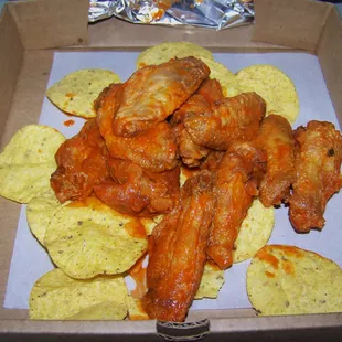 Mild buffalo wings on top a bed of chips.
