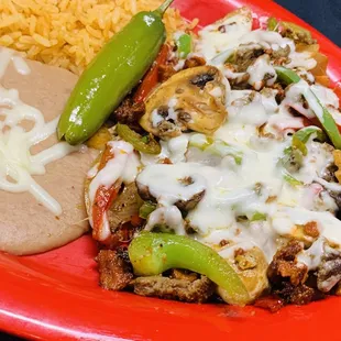 Alambre- steak and Al pastor sautéed with green peppers, onion, and mushroom covered with  cheese. Served with rice and beans.