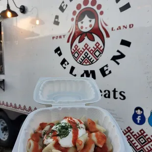 a container of food in front of a food truck