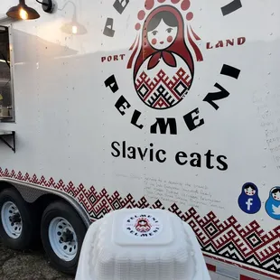 a person holding a plate of food in front of a food truck