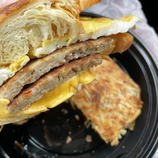 Breakfast croissant sandwich w a side of hash browns.