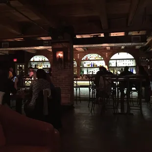 people sitting at tables in a dimly lit bar