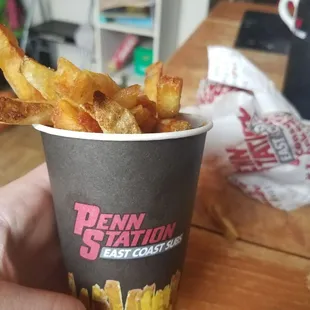 a person holding a cup of fries