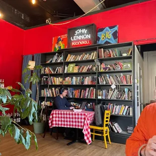a woman sitting at a table in front of a bookshelf