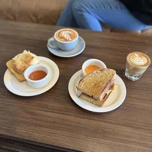 Bacon breakfast sandwich, biscuit and jam, cappuccino and cortado.