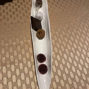a long white plate with desserts on it