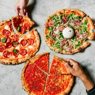 three pizzas being sliced