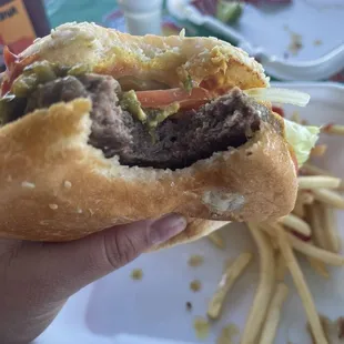 a person holding a hamburger and french fries