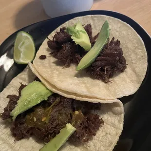 two beef tacos on a black plate