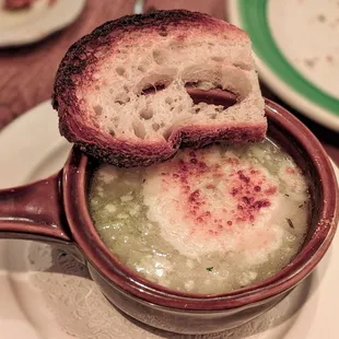 a bowl of soup with a piece of bread sticking out of it