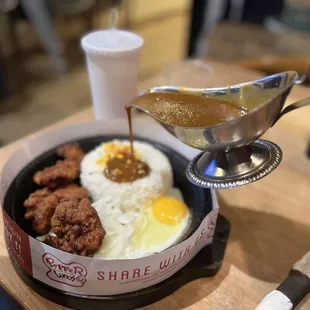 a person pouring gravy over a bowl of food