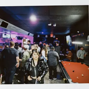 a group of people standing around a pool table