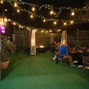 people sitting at a table under a string of lights