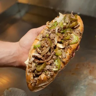 a hand holding a sub sandwich