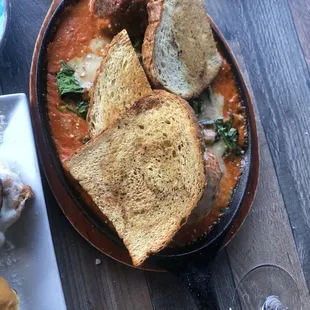 Very well-spiced meatball appetizer with a creamy tomato sauce, some spinach, cheese, and crunchy toast