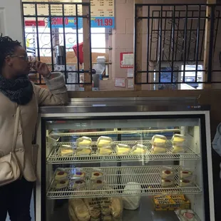 a woman standing in front of a display case of donuts