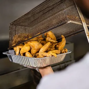a man holding a tray of fried chicken