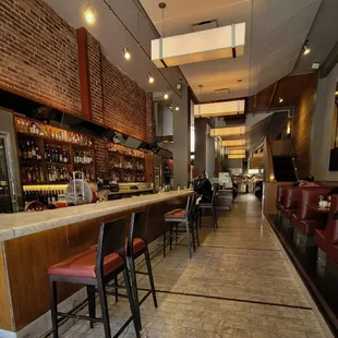 a long bar with red leather chairs
