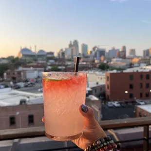 a person holding a drink with a cityscape in the background