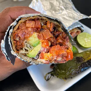 a person holding a burrito in their hand