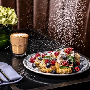 a plate of french toast with berries and powdered sugar