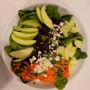 a salad with apples, carrots, and spinach