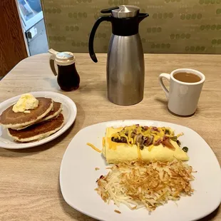 a breakfast of eggs, hash browns, and pancakes