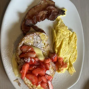 Strawberry croissant French toast with scrambled eggs and bacon