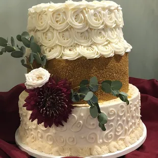 a three tiered wedding cake with white frosting and red flowers