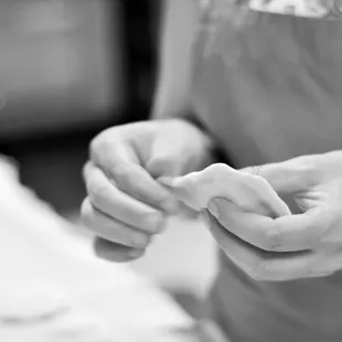 a black and white photo of a woman making doughnuts