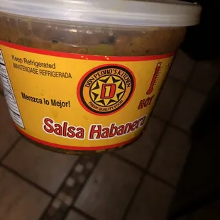a person holding a container of salsa habanea