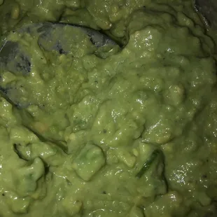 a bowl of guacamole with a spoon in it