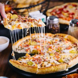 a person taking a slice of pizza