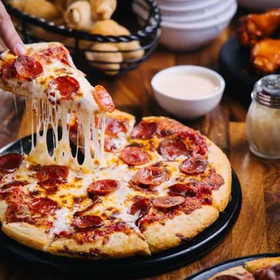 a person taking a slice of pizza