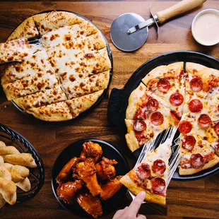 a person cutting a slice of pizza