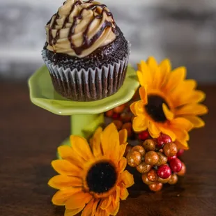 a cupcake on a green cake stand with sunflowers