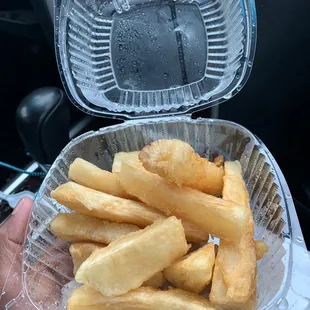a hand holding a container of french fries