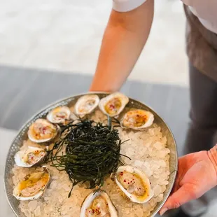 a person holding a platter of oysters